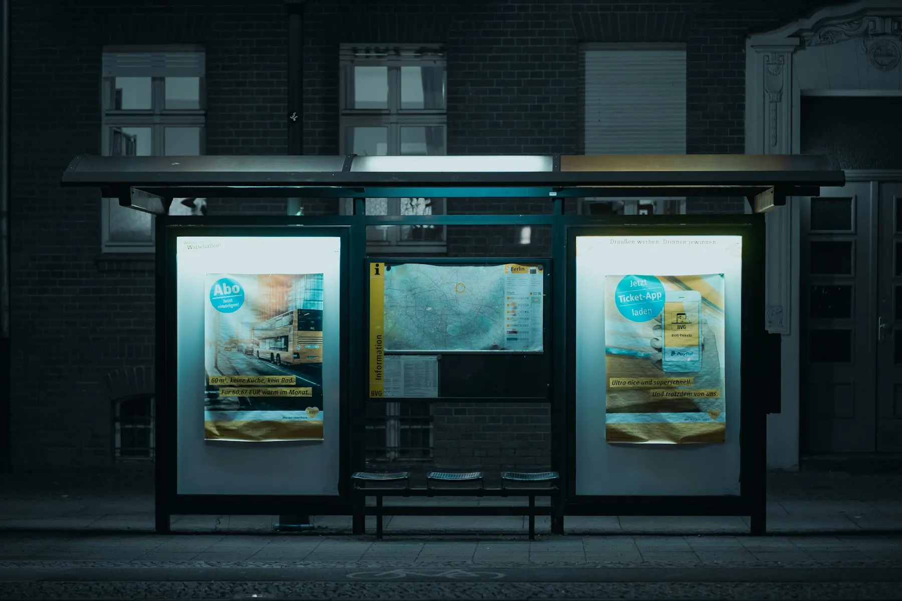 Una parada de autobús vacía iluminada de noche, sin personas.