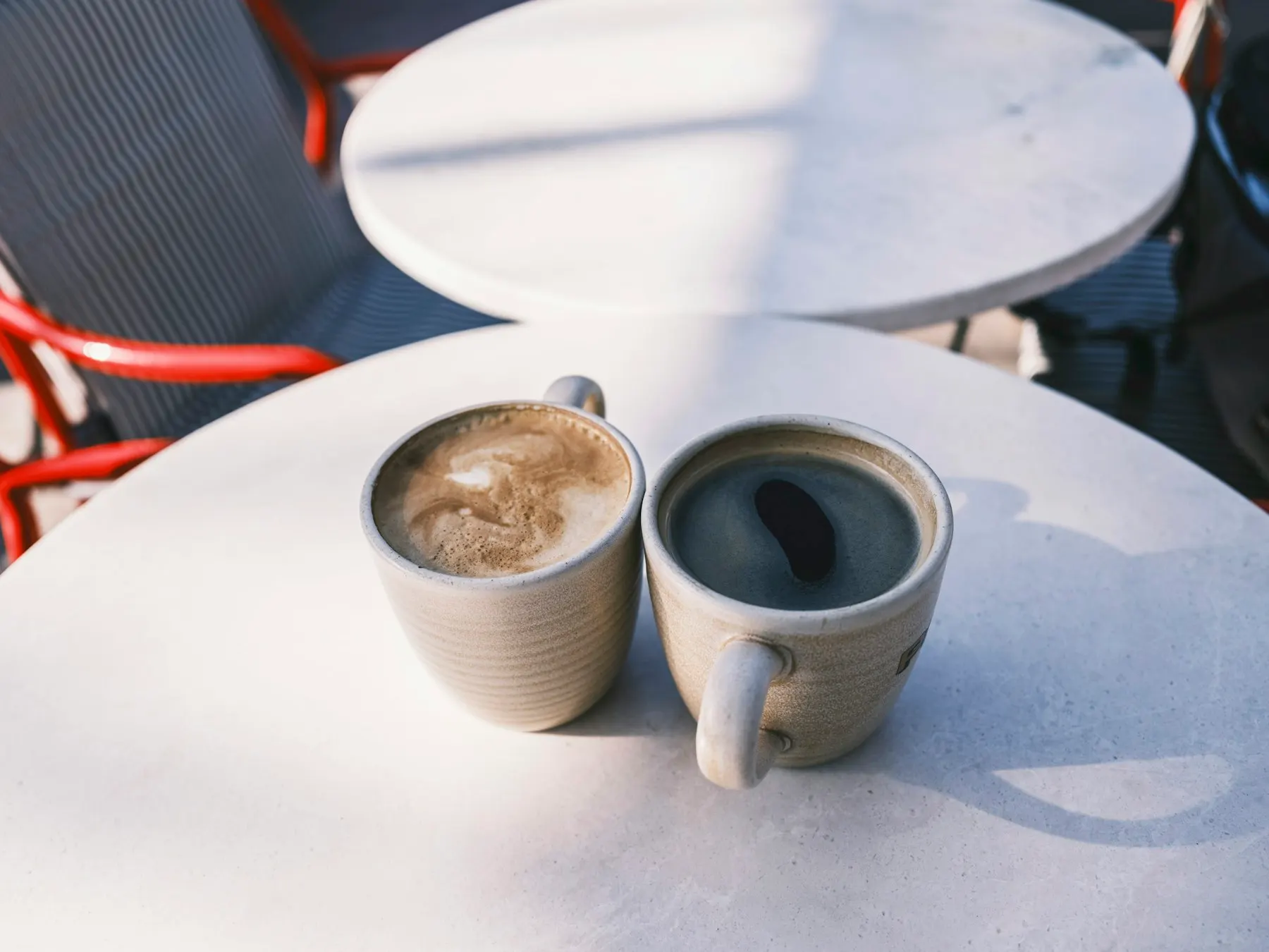 Dos tazas de café servidas sobre una mesa blanca, listas para compartir.