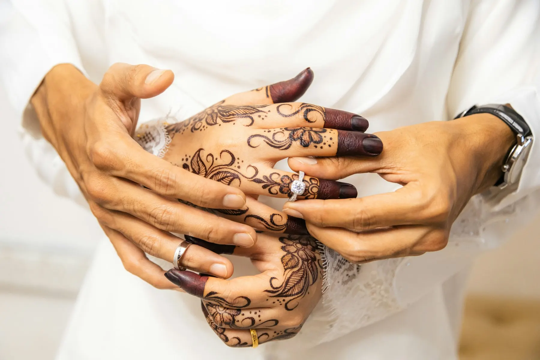 Unas manos decoradas con henna sostienen las manos de otra persona.
