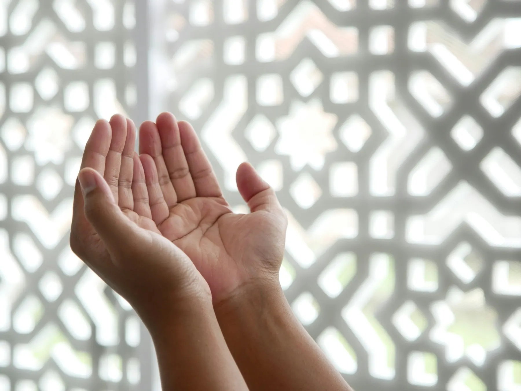 Unas manos abiertas en actitud de súplica, con luz cálida de atardecer y unas cuentas de tasbih al lado.