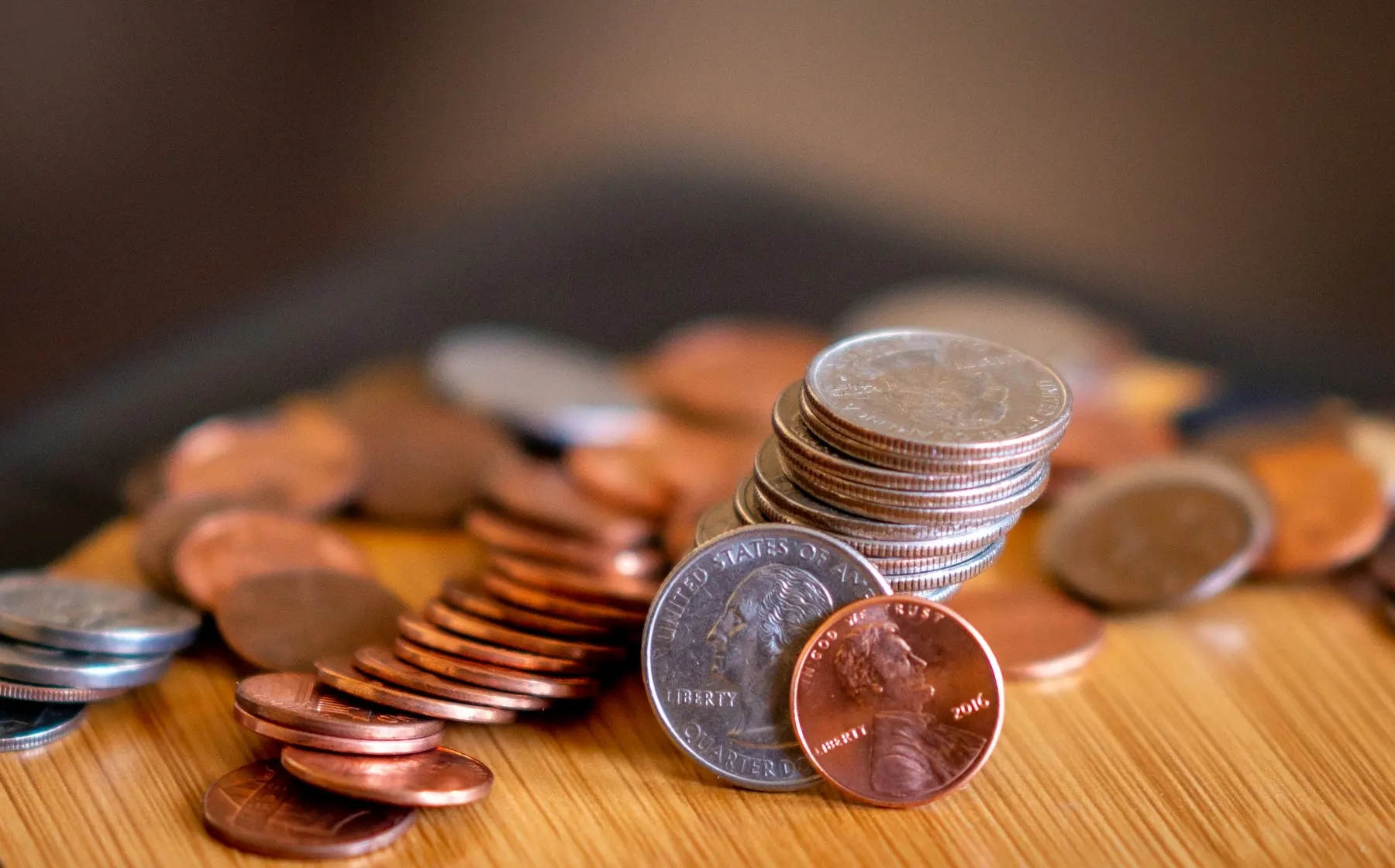 Una calculadora, una chequera y unas monedas ordenadas sobre una mesa de madera.