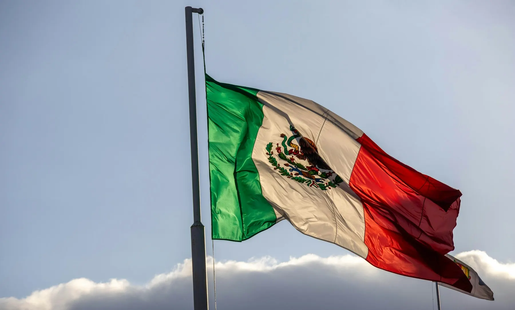 Una persona con hiyab sostiene una credencial de elector frente a una casilla de votación en México.