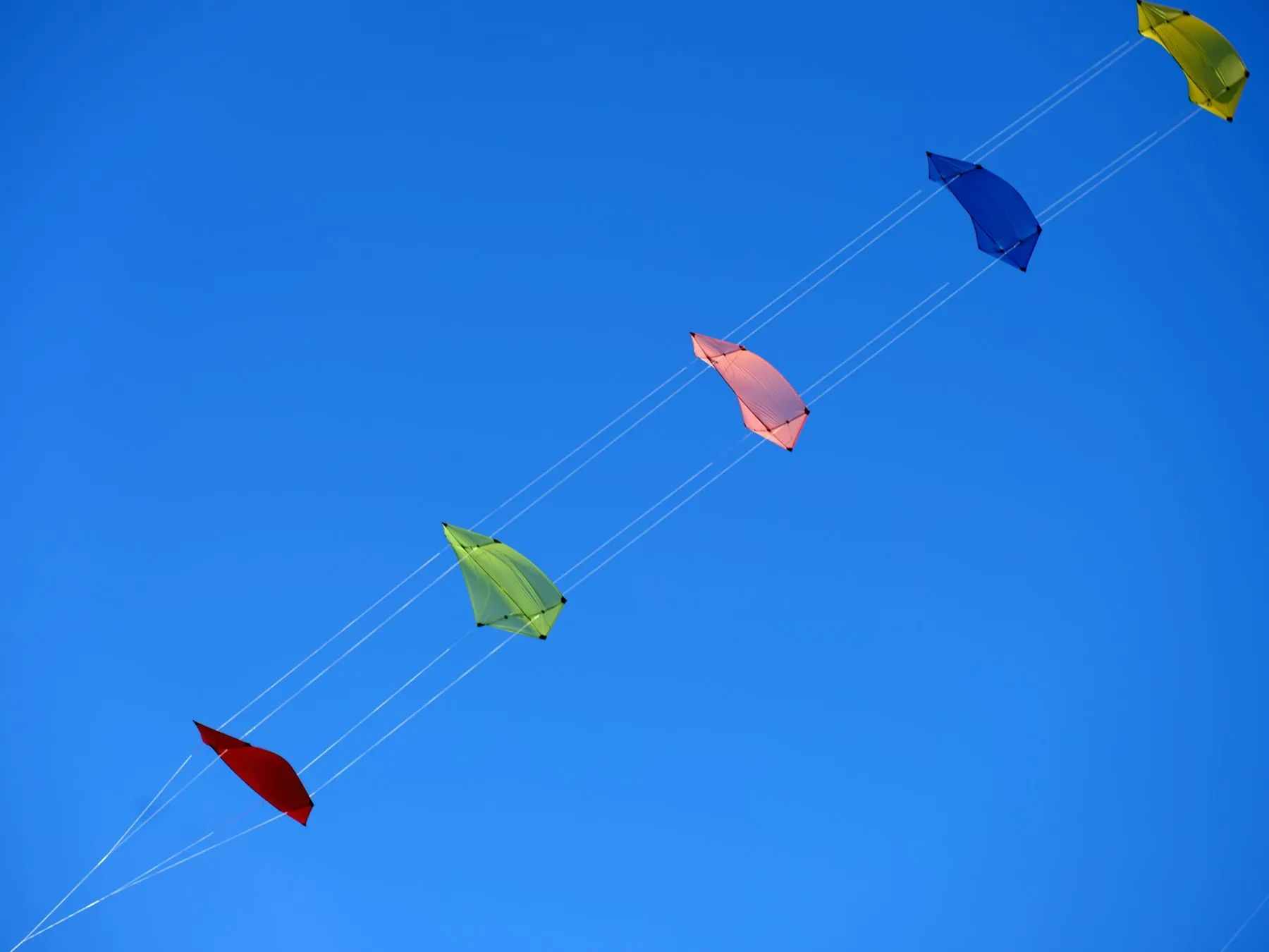 Una cometa de tela roja volando alto contra un cielo azul despejado.