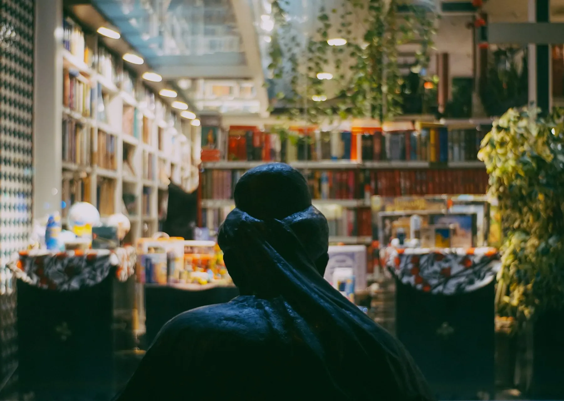 Una mujer con hiyab, de espaldas, busca un libro entre las estanterías de una biblioteca.
