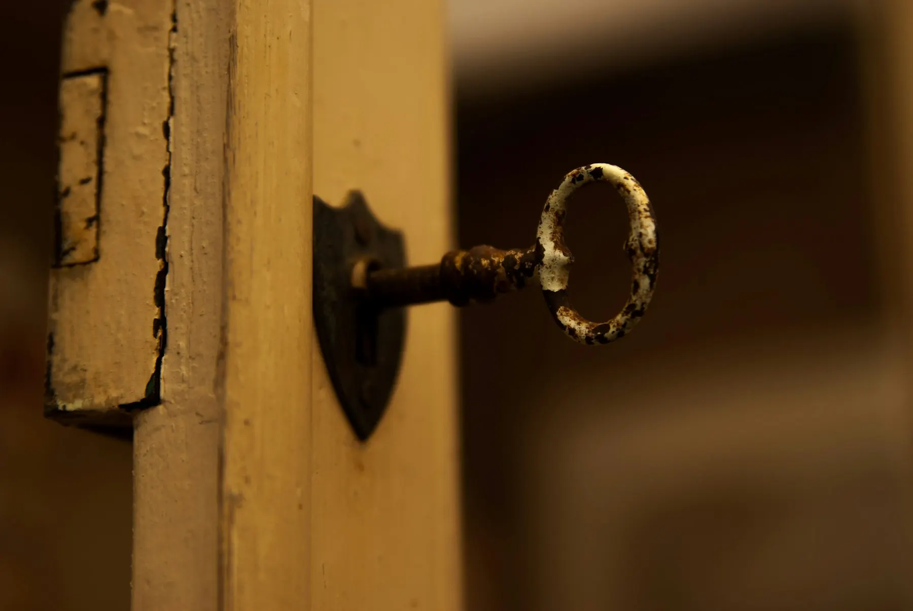 Una llave antigua de hierro colocada en la cerradura de una puerta de madera.