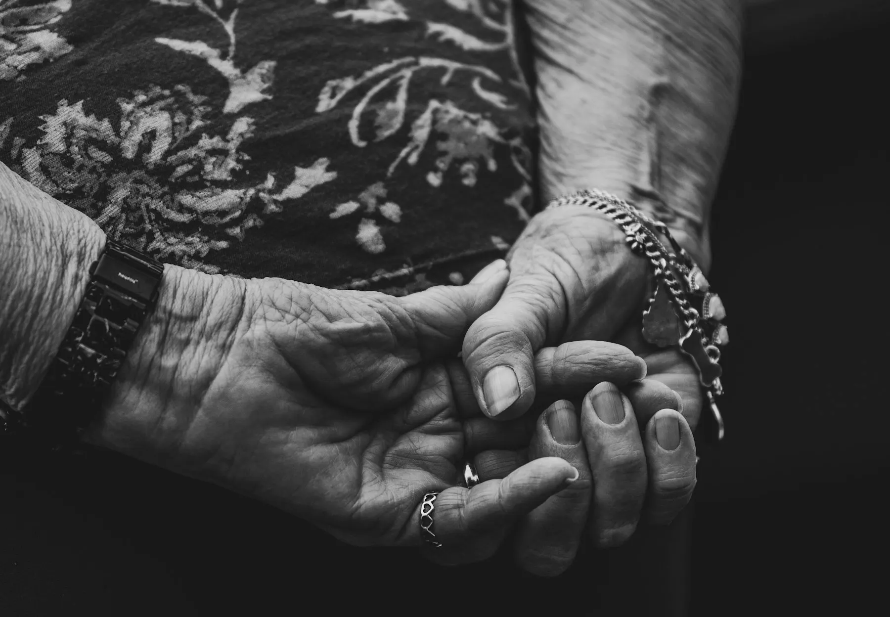 Las manos de una persona mayor sobre las manos de un adulto joven, en un gesto de apoyo, sin rostros.
