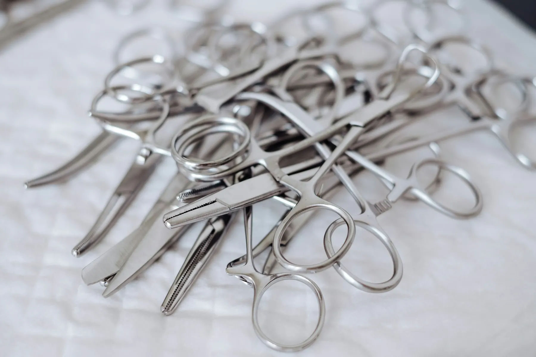 Instrumentos quirúrgicos antiguos de metal dispuestos sobre un paño oscuro.