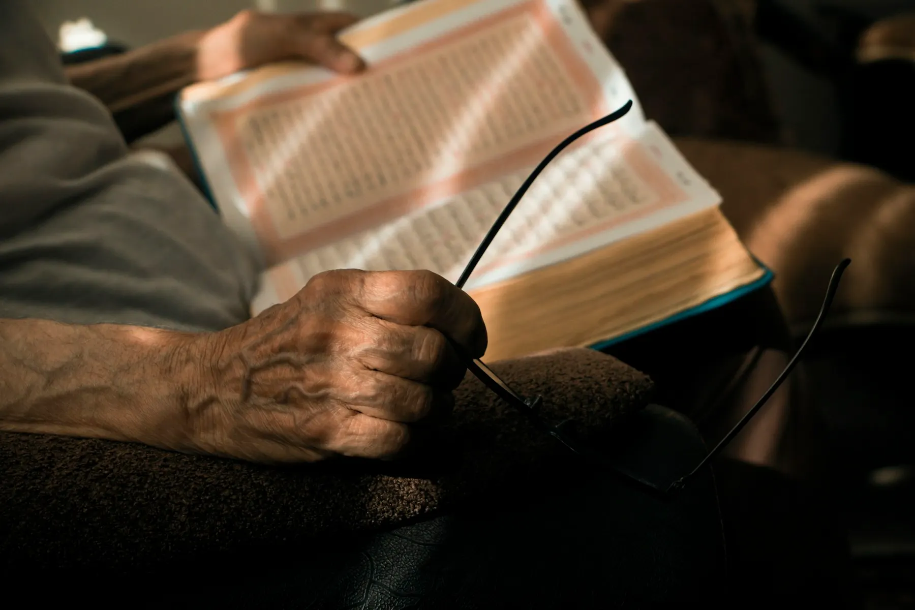Una mano sostiene un libro abierto en un ambiente de luz cálida y suave.