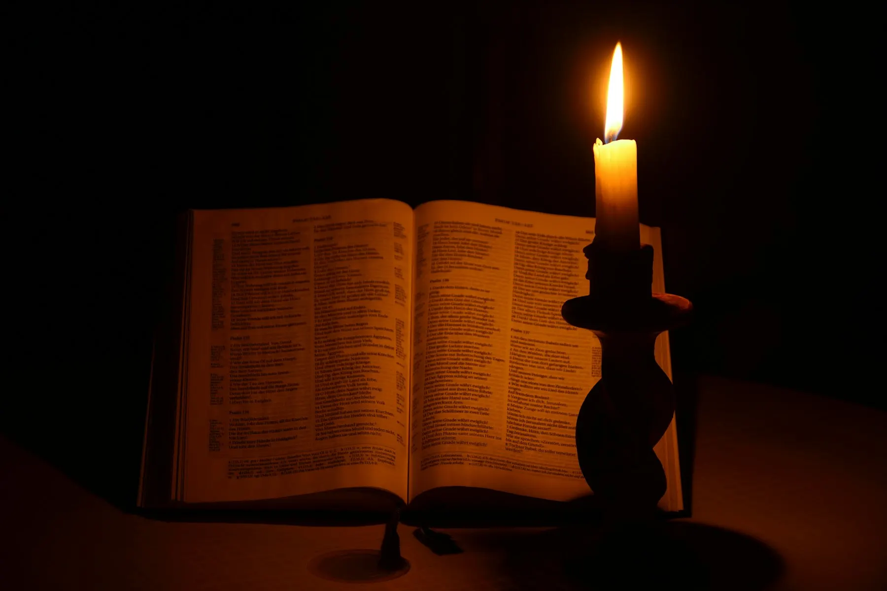 Un libro abierto junto a una vela encendida en un ambiente cálido y sereno.