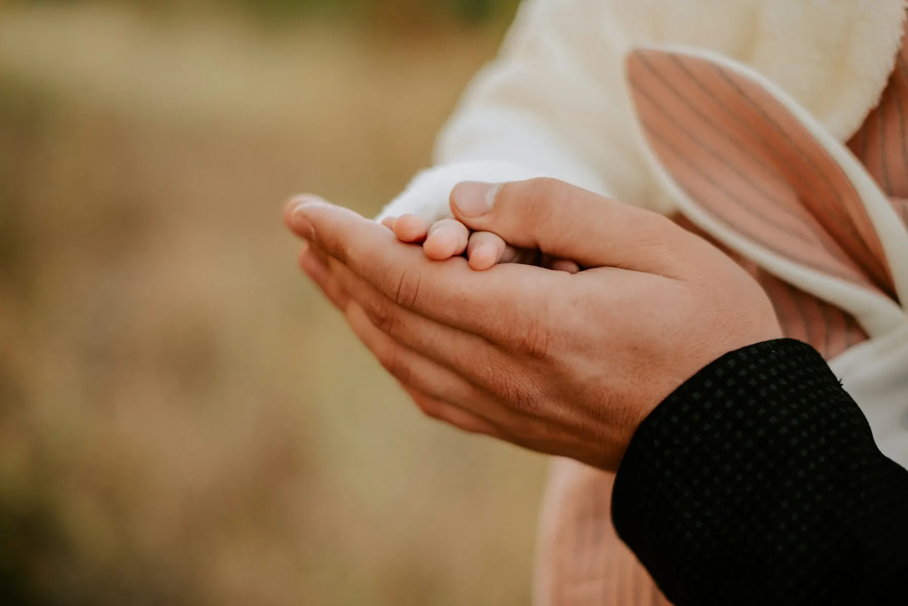 La mano pequeña de un niño descansa en las manos de su madre.
