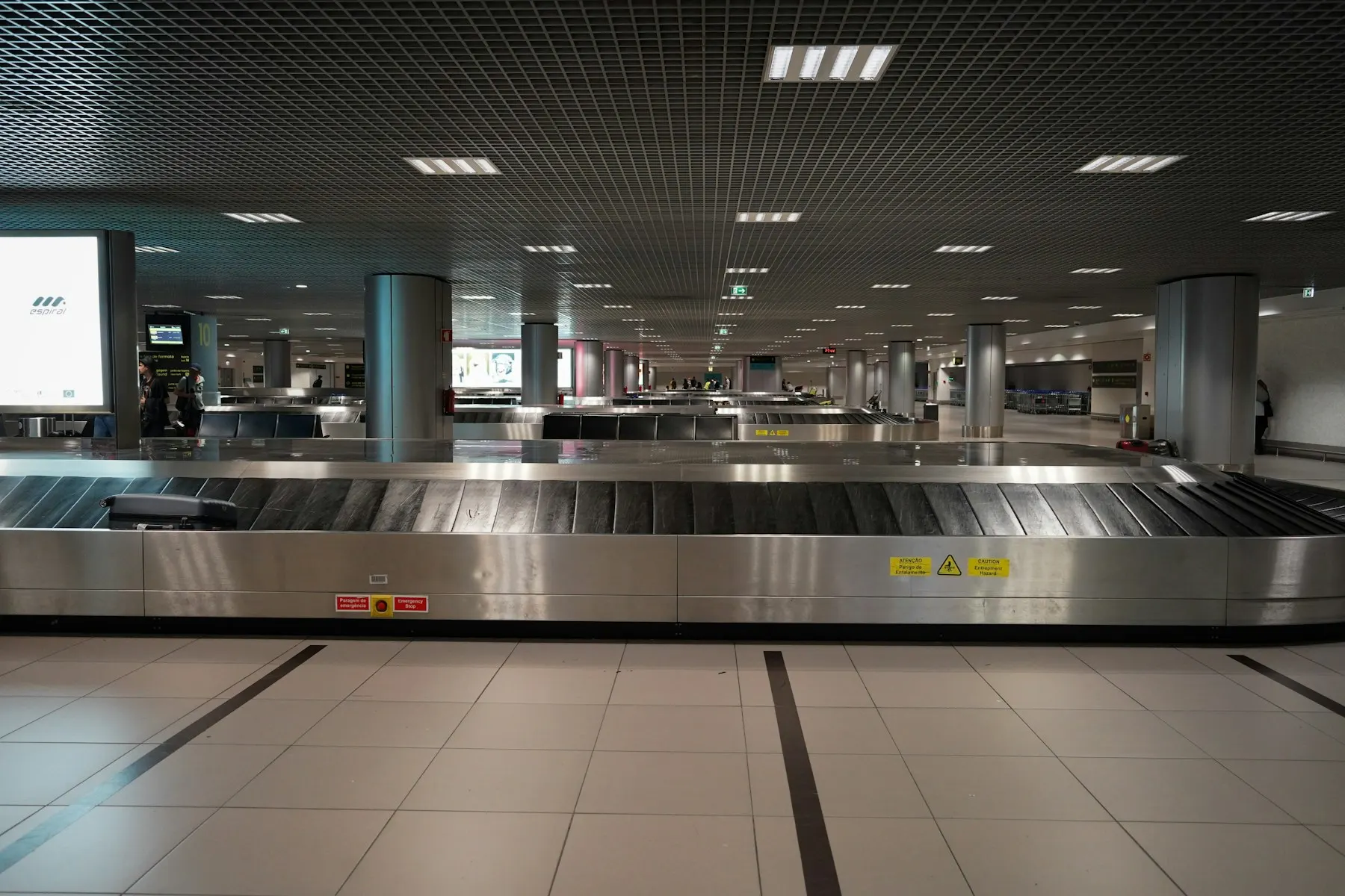 La banda de equipaje vacía de un aeropuerto, con una sola maleta, sin personas cerca.