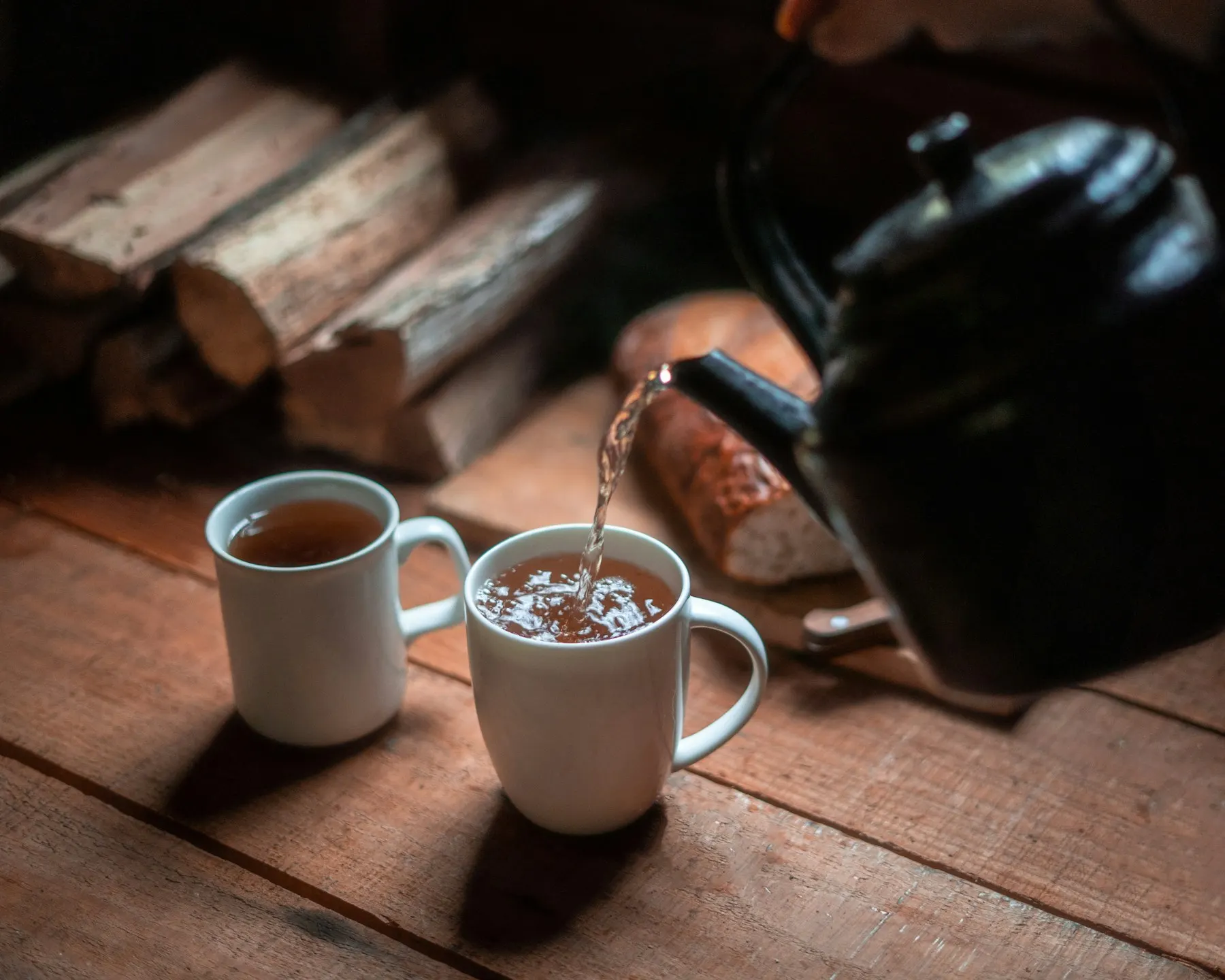 Dos tazas de té servidas sobre una mesa de madera, a la luz cálida de una lámpara.