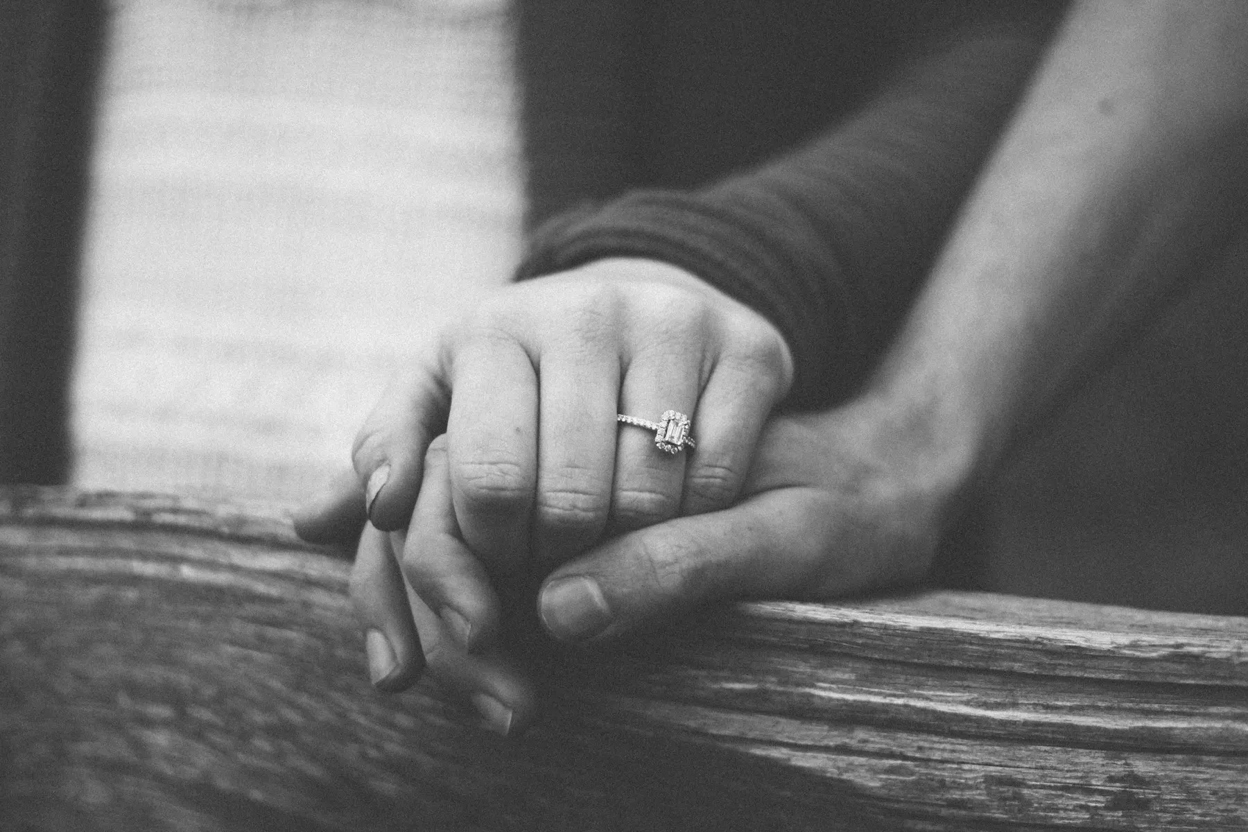 Las manos entrelazadas de una pareja, sin rostros visibles, sobre una manta tejida.